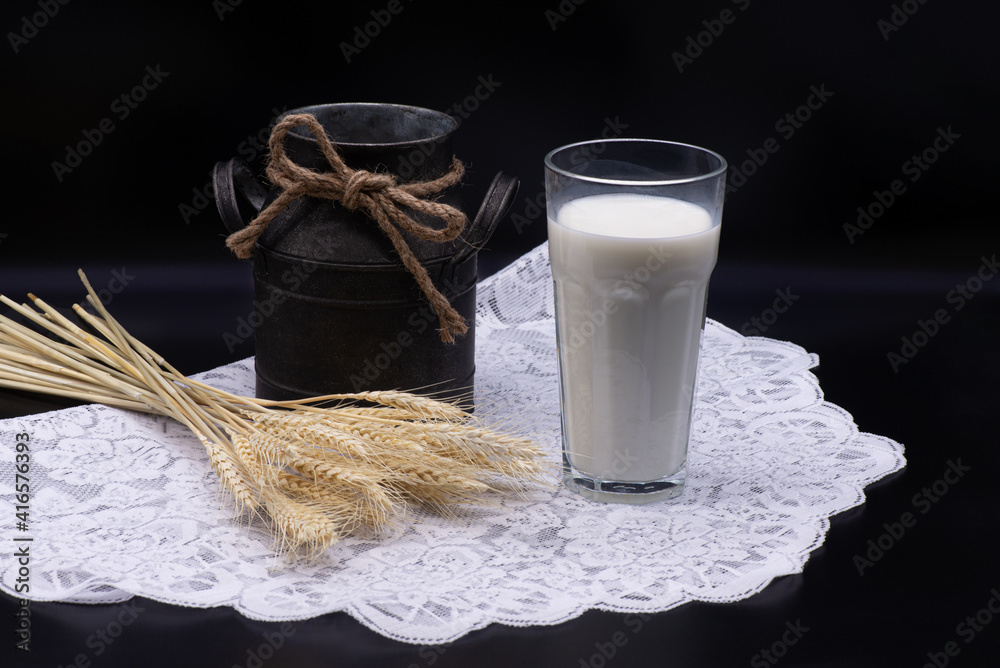 Composition of glass of milk, wheat, an old jug on a white tablecloth