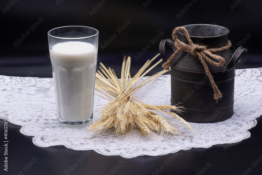 Composition of glass of milk, wheat, an old jug on a white tablecloth