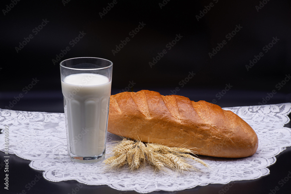 Composition of glass of milk, wheat, white bread on a white tablecloth