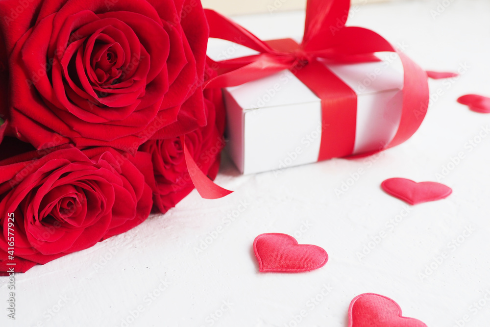 three red roses and a gift box with a bow on a white table and red hearts.. three red roses and a gift box with a bow on a white table and red hearts..