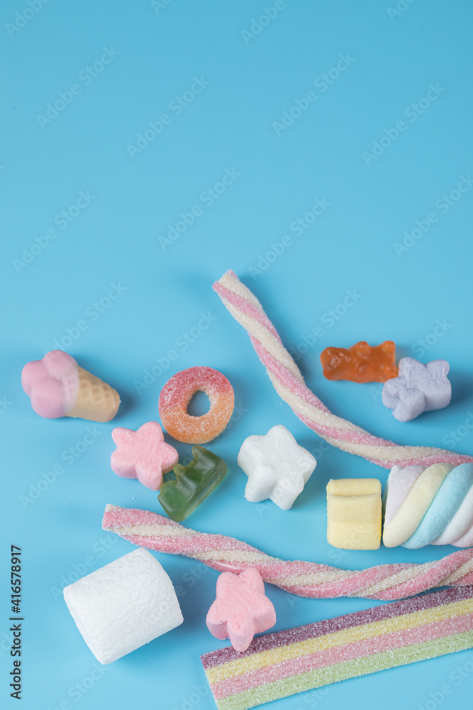 Jellybeans and marshmallow mix on a blue background - obrazy, fototapety, plakaty 