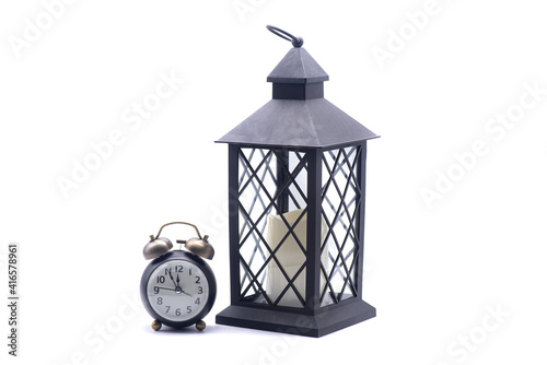 Obraz na płótnie Glass lamp with a candle inside and retro alarm clockon a white background w salonie
