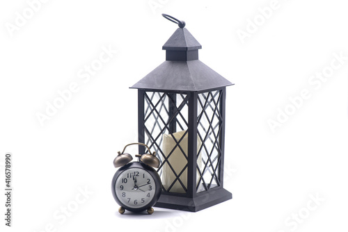 Obraz na płótnie Glass lamp with a candle inside and retro alarm clockon a white background w salonie