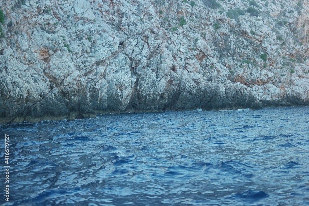 Rocky shore and blue calm sea. Beautiful limestone rock on the coastline of the sea.