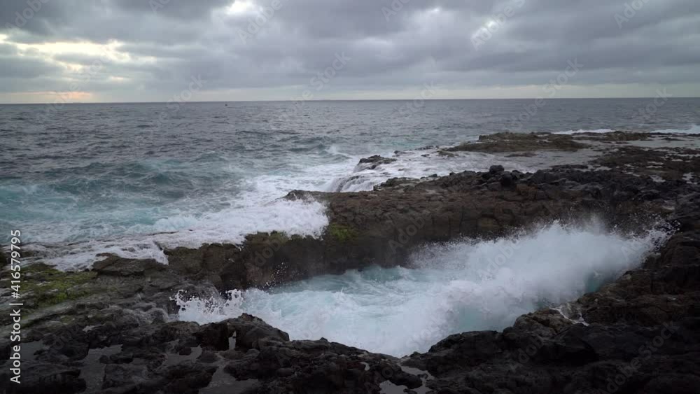 Slow motion big waves breaking on the rocky beach, rock hole where the water enters and leaves. Slow motion big waves breaking on the rocky beach, rock hole where the water enters and leaves.