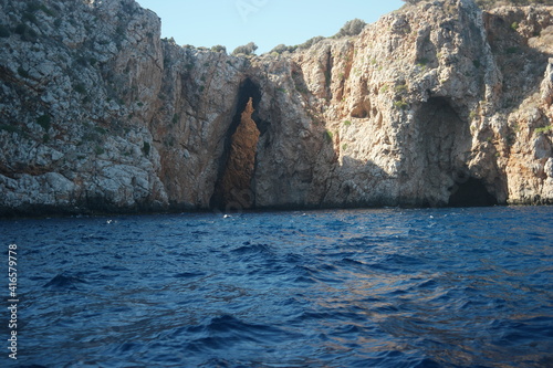 Calm sea waves washing big rocky cliff. Rocky formation in sea water. Tranquil nature scene.