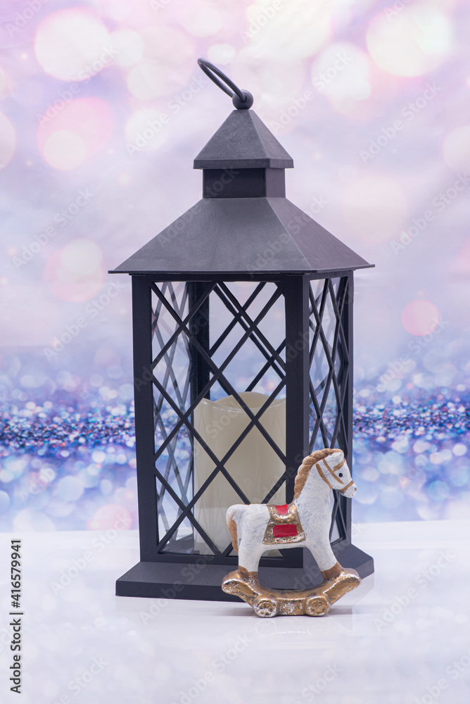 Glass lamp with a candle inside and toy horse on a festive background