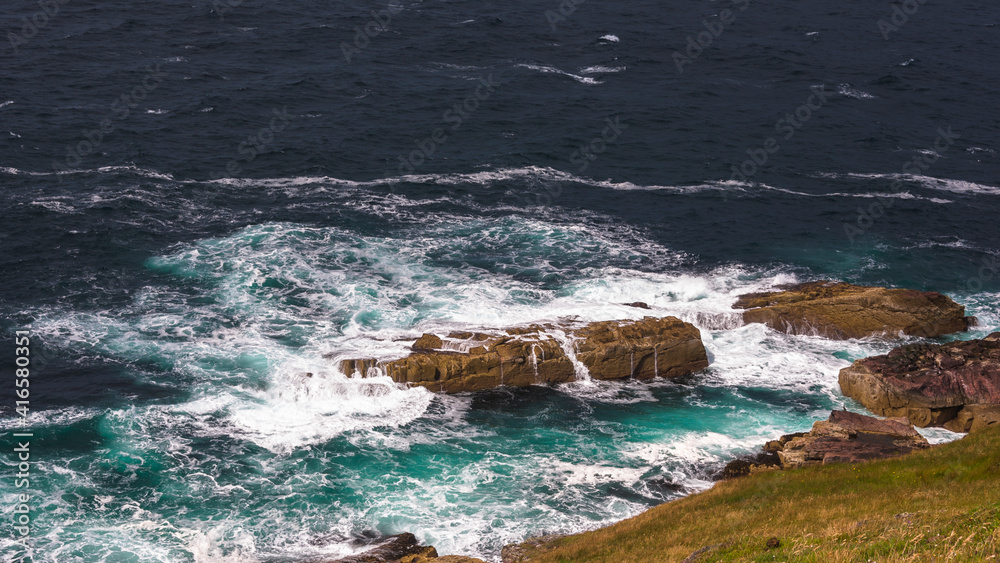 Stoer lighthouse view on wild ocean waves rocks
