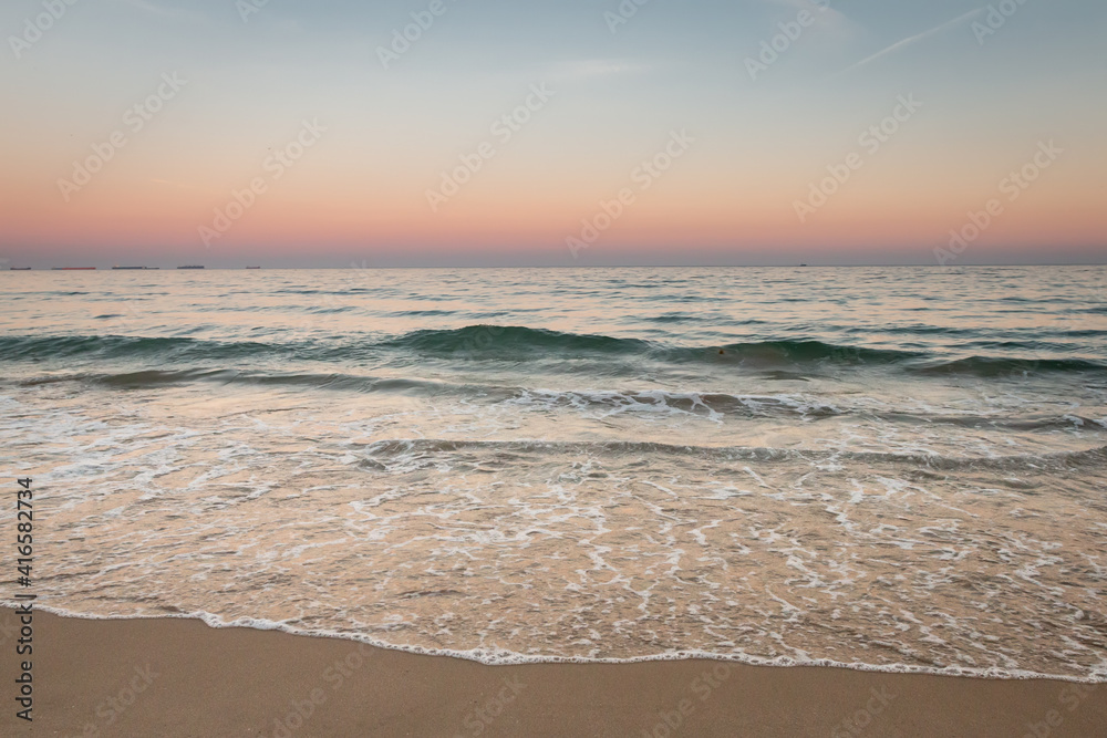 Sea waves on the beach with sunset sky background.