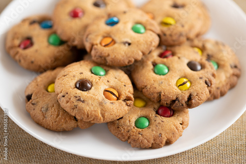 Cookies with colorful M&Ms chocolates close-up on a white plate.