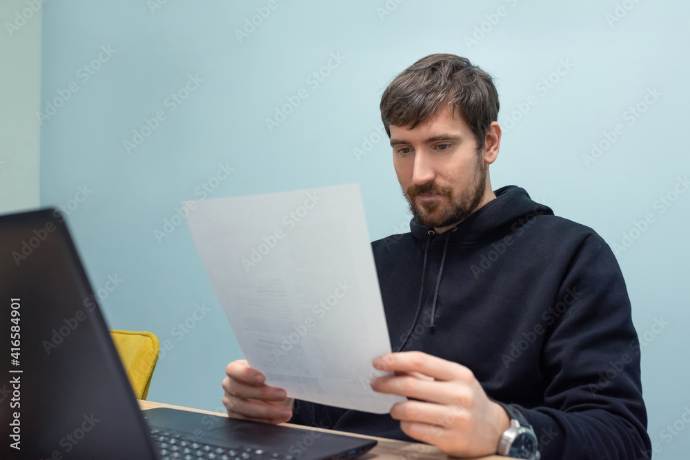 Young man working in the office with documents sitting at his desk. Business, training Young man working in the office with documents sitting at his desk. Business, training