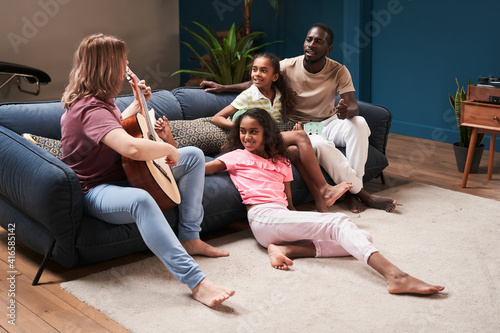 Woman patiently teaching her daughter playing at the guitar
