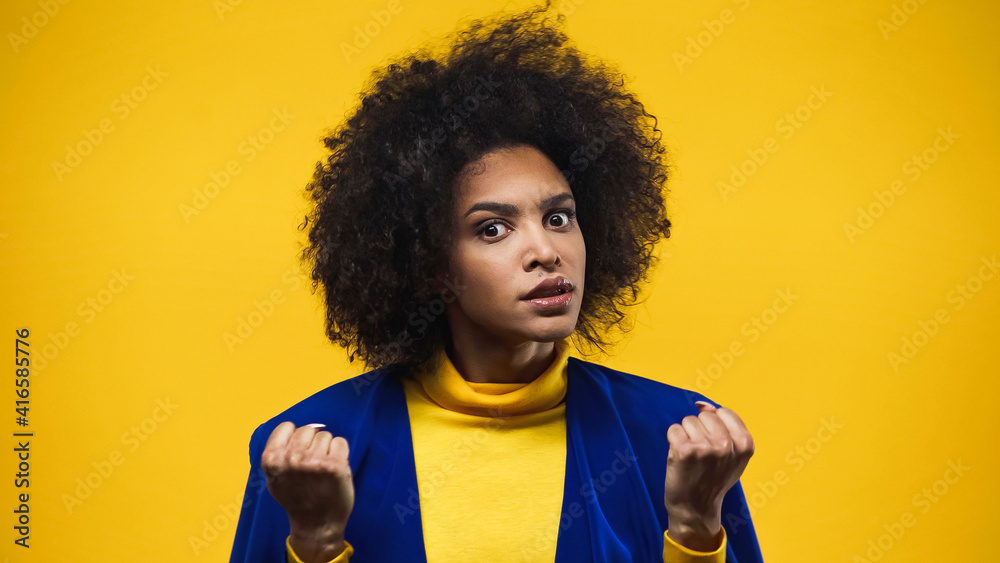Angry african american woman showing fists isolated on yellow