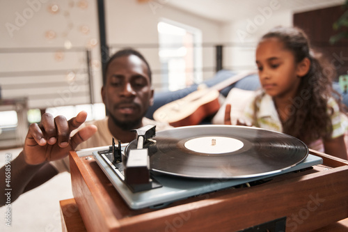 Man listening music on vinyl records with his daughters photo