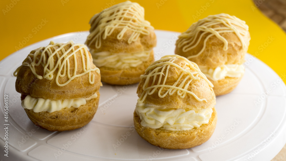 Choux Cream Puff Custard Whipped Cream Filling on a wooden plate Choux Cream Puff Custard Whipped Cream Filling on a wooden plate