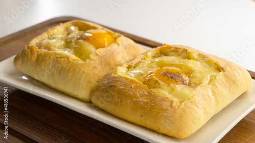 Baked Egg Ciabatta Boats. ciabatta with egg on a wooden plank 