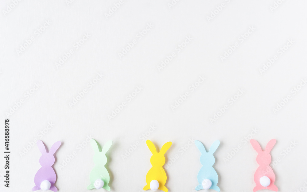 Easter background in the style of minimalism. Copy space. On a light wooden background, there are figures of Easter bunnies.
