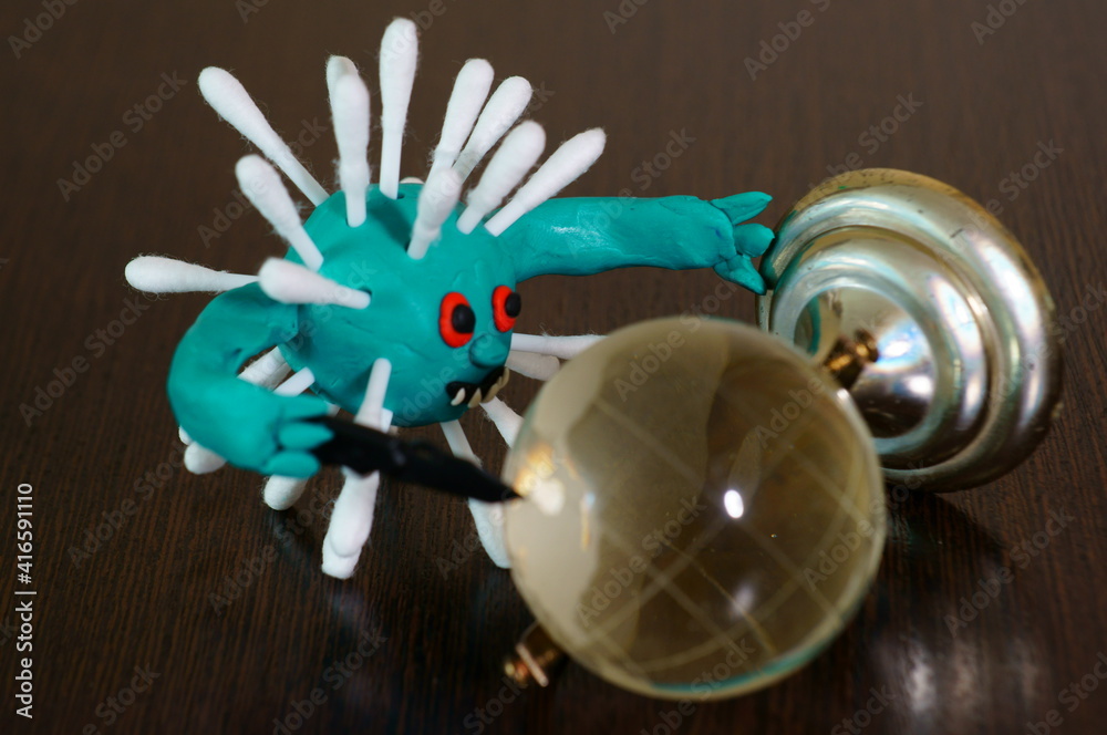 Fototapeta premium Figure of a virus with a toy knife. Next to it is a small glass globe.
