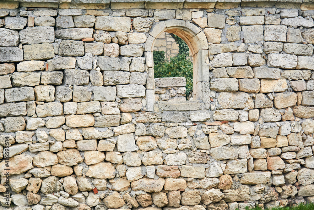 stone wall of an ancient building with a semicircular window, beyond which other ruins are visible stone wall of an ancient building with a semicircular window, beyond which other ruins are visible