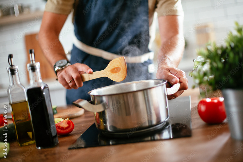 Handsome man preparing pasta in the kitchen. Close up of guy cooking a tasty meal. Handsome man preparing pasta in the kitchen. Close up of guy cooking a tasty meal.