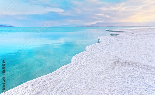 Morning scenery - white salt crystals beach, clear water near, typical landscape at Dead Sea shore, Israel