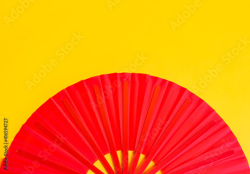 Red hand fan on yellow background  top view