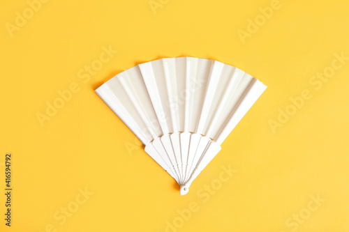 White hand fan on yellow background  top view