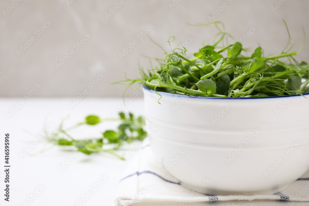 Bowl with fresh microgreen on white table, closeup. Space for text