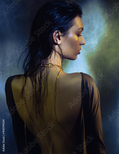 A young beautiful female model poses in the studio. Dark vintage fashion portrait. Long exposure and light brush.