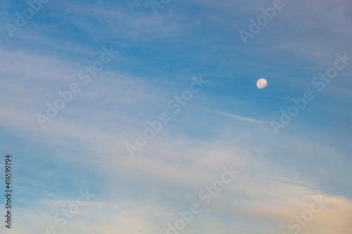 White clouds and the moon in a blue sky