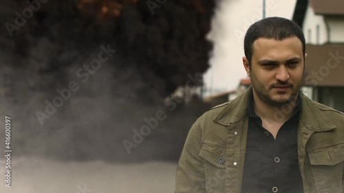 cool guy walks in the background of a car explosion