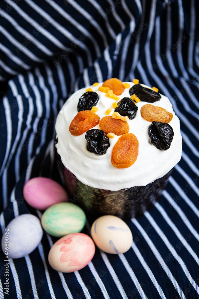 Easter eggs and Easter cake lie on a striped blue apron. Easter religious holiday concept. Easter eggs and Easter cake lie on a striped blue apron. Easter religious holiday concept.