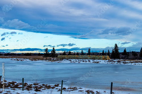 Haybales sitting by a frozen pond. Sibbald Creek Trail, Alberta, Canada