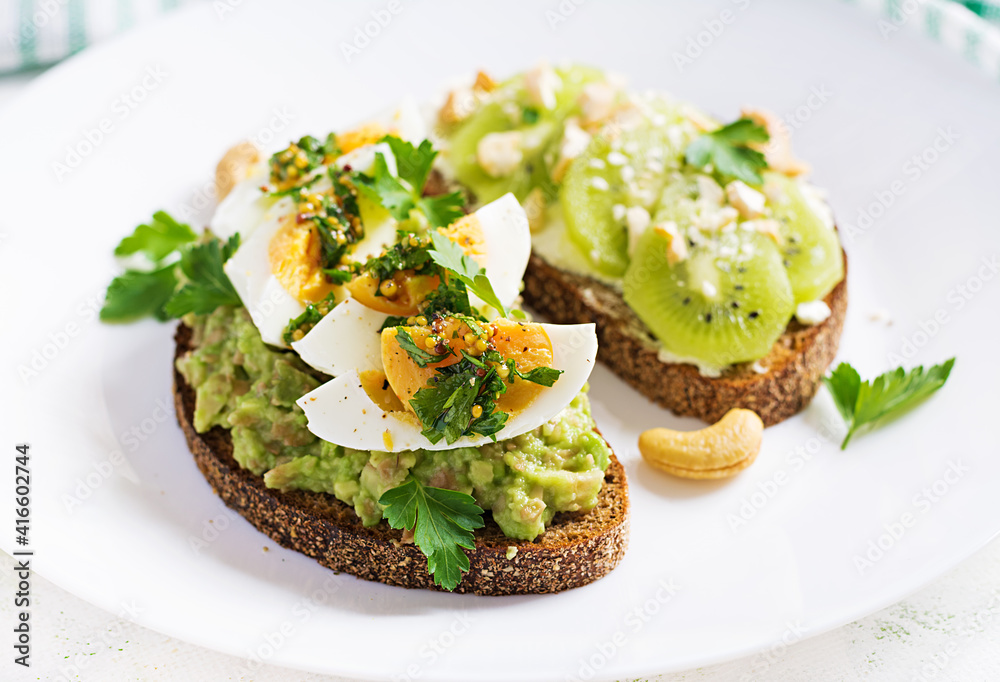 Vegetarian breakfast. Sandwich with avocado puree, boiled eggs and sandwich cream cheese, kiwi, nuts.  Healthy breakfast or lunch.