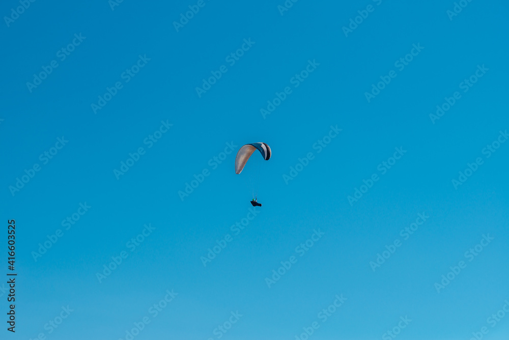 Man flying on a paraglider against the blue sky Man flying on a paraglider against the blue sky