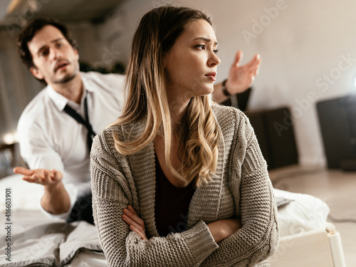 Boyfriend and girlfriend are arguing at home. Angry man is yelling at his sad girlfriend. photo