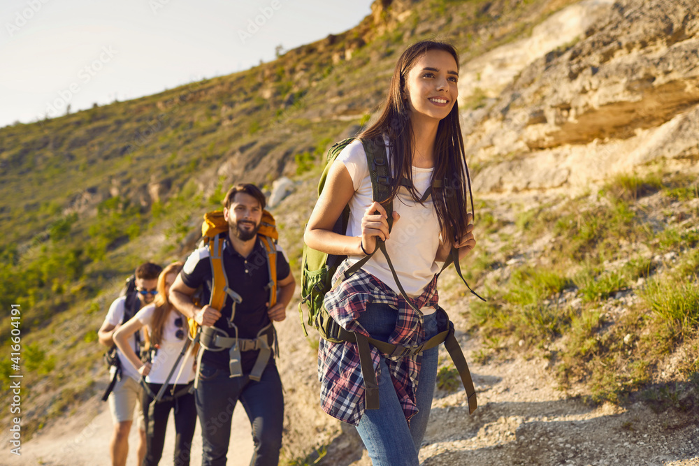 © Studio Romantic - Group of friends tourists with backpacks traveler in the mountains on a hike hiking along the route in nature in summer.