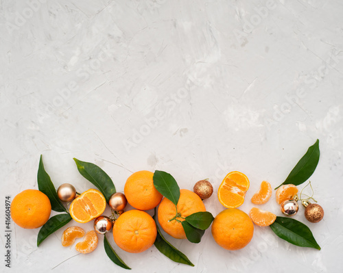 Tangerines: whole, cut and lobules, decorated by golden little balls, green leaves and spruce twigs, on grey background. Fruits contain many vitamins good for healthy. © vera