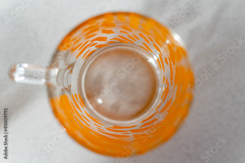 a single glass cup with a orange pattern on a white background from above 
