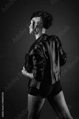 Attractive young woman from back, with punk hairstyle, wearing leather jacket and fishnet stockings