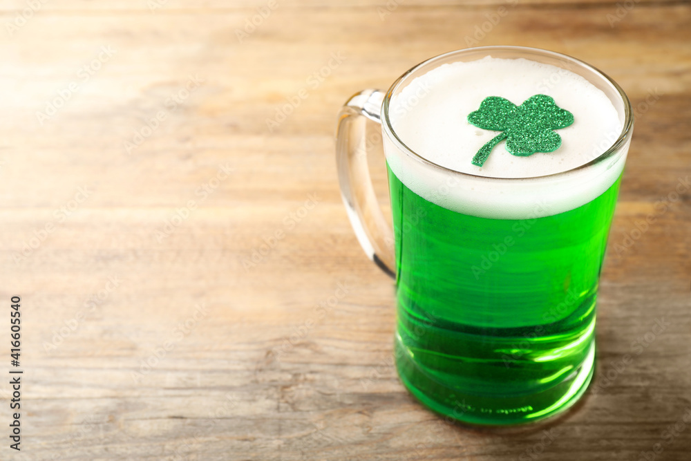 Glass of green beer with clover leaf on wooden table, space for text. St Patrick's Day celebration Glass of green beer with clover leaf on wooden table, space for text. St Patrick's Day celebration