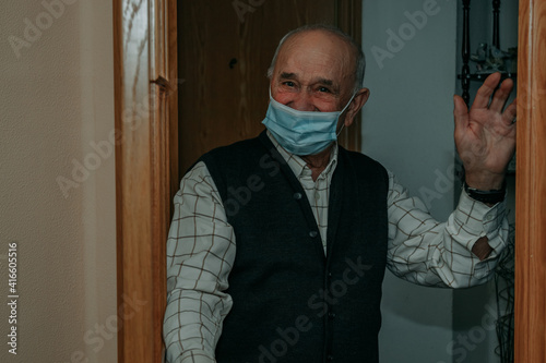 old man or senior with face mask at home at the door photo