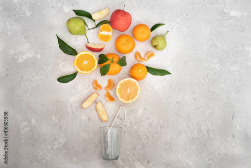 Many different fruits: tangerines, oranges, grapefruits, lemon, apples and pears on grey background. All vitamins fit in one glass. Many vitamins fresh juices are good for healthy lifestyle.