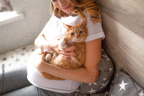 Pregnant woman playing with cat in the bed