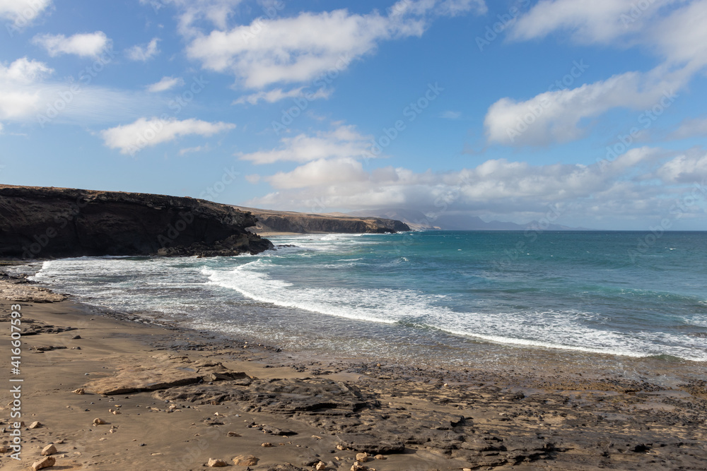 Ocean view on la Pared beach. Beautiful view of the clear sea, waves, cliffs and beach in Playa de la Pared - Canary Islands, Fuerteventura, Spain. 