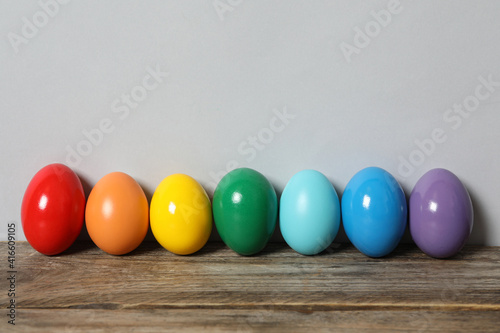 Easter eggs on wooden table against light grey background, space for text