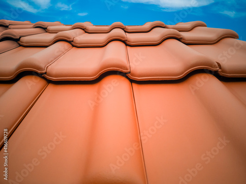 Close-up several horizontal rows of new anthracite clay tiles for sale in German building materials store,blue sky.Detail of finished roof in Europe,covered with tiles, view from outside.Copy space