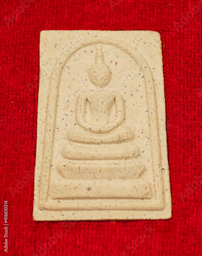 Macro Thai buddha amulet on the red velvet background.    photo