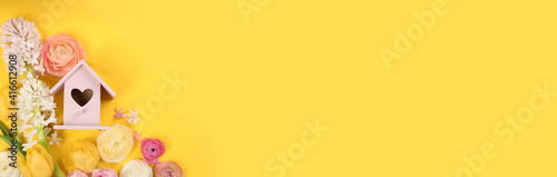 Stylish bird house and fresh flowers on yellow background, flat lay. Space for text