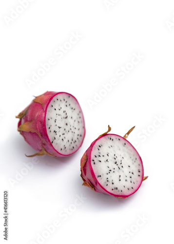 Two halves of a dragon fruit with white flesh. The pink pitaya fruit is low in calories, rich in essential vitamins and minerals, and contains dietary fiber.